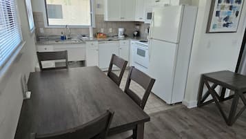 A kitchen with white cabinets, a wooden table, and chairs.