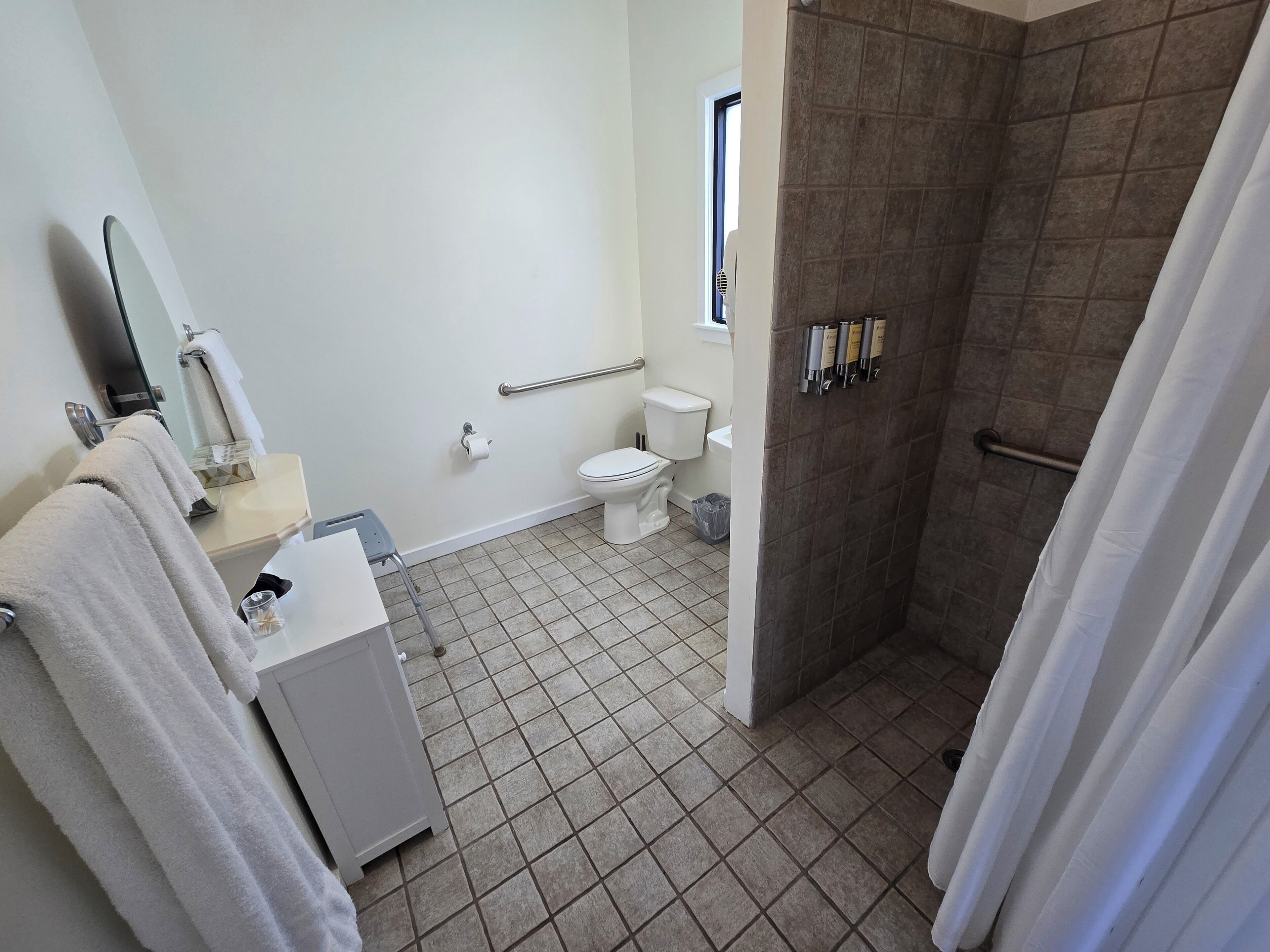 Ein Badezimmer mit Toilette, Waschbecken, Spiegel, Handtuchhalter und einer Duschkabine.