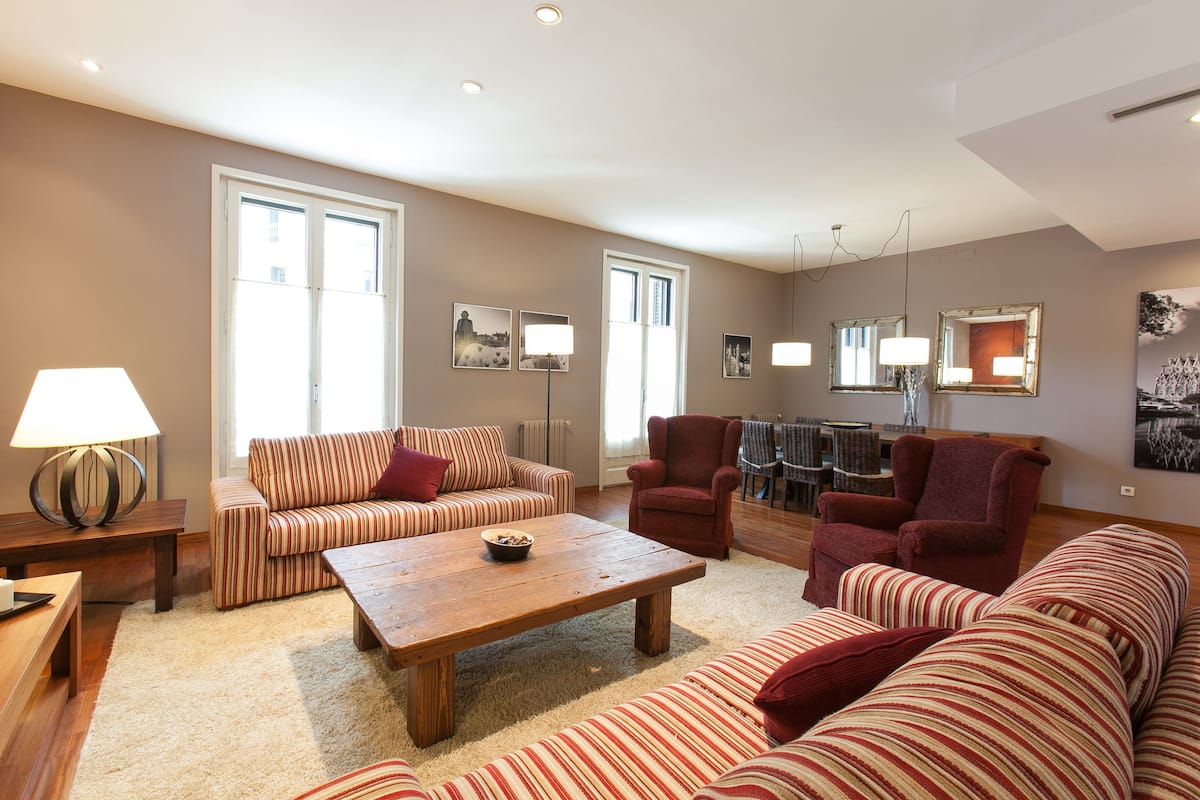 A spacious living room with striped sofas, a wooden coffee table, and a red armchair.