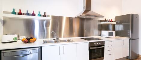 Una cocina moderna con electrodomésticos de acero inoxidable, lavavajillas y microondas.