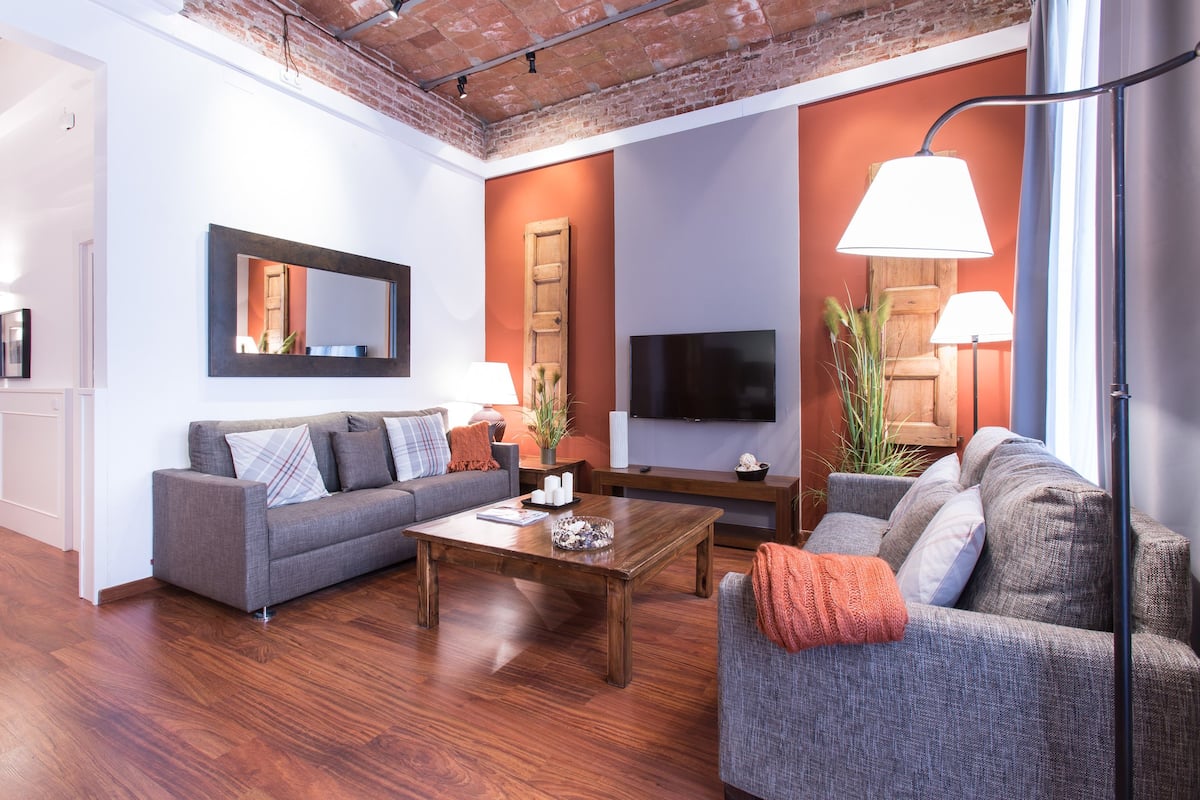 A modern living room with a grey sofa, a wooden coffee table, and a flat-screen TV.