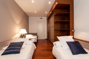 A hotel room with two single beds, a wooden wardrobe, and a door leading to another room. - Serennia Apartments Ramblas-Pl.Catalunya (Barcelona)