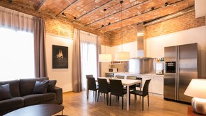 Una cocina moderna con comedor, que presenta techo de ladrillo, electrodomésticos de acero inoxidable y un diseño contemporáneo.