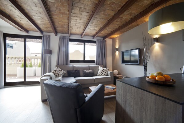 A modern living room with a sofa, a coffee table, and a fruit bowl on a counter.