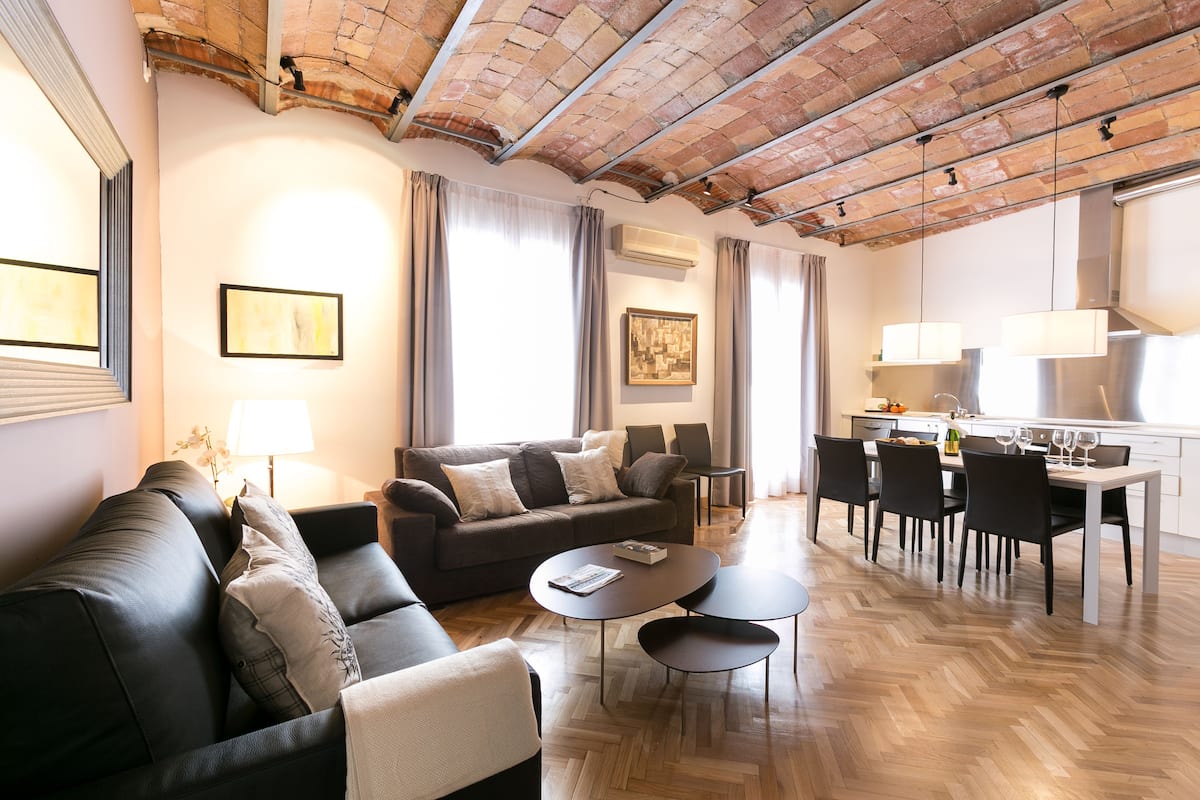 A modern living room with a sofa, coffee table, and dining area.