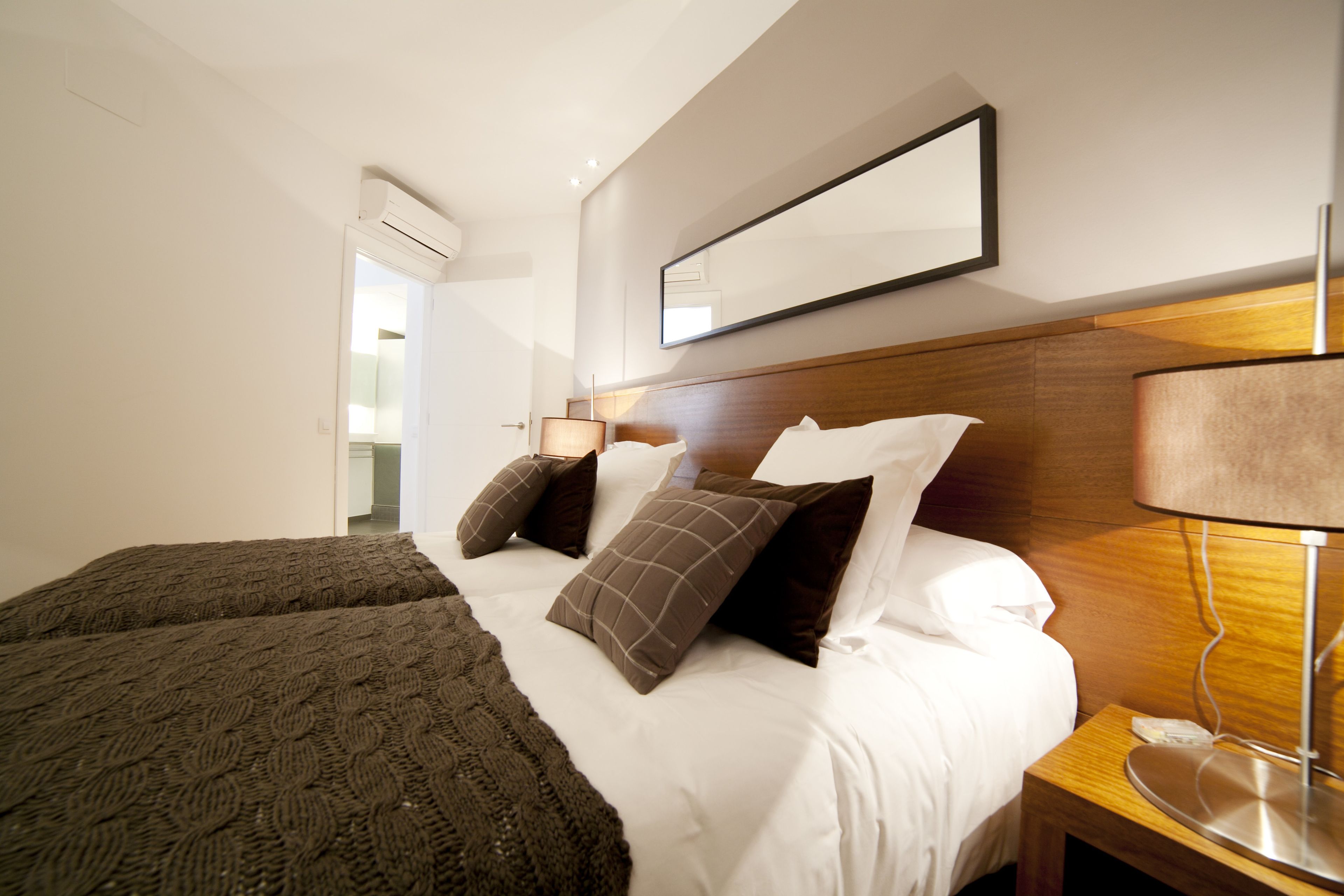 Ein Hotelzimmer mit einem großen Bett, einem Nachttisch mit einer Lampe und einem Spiegel an der Wand.