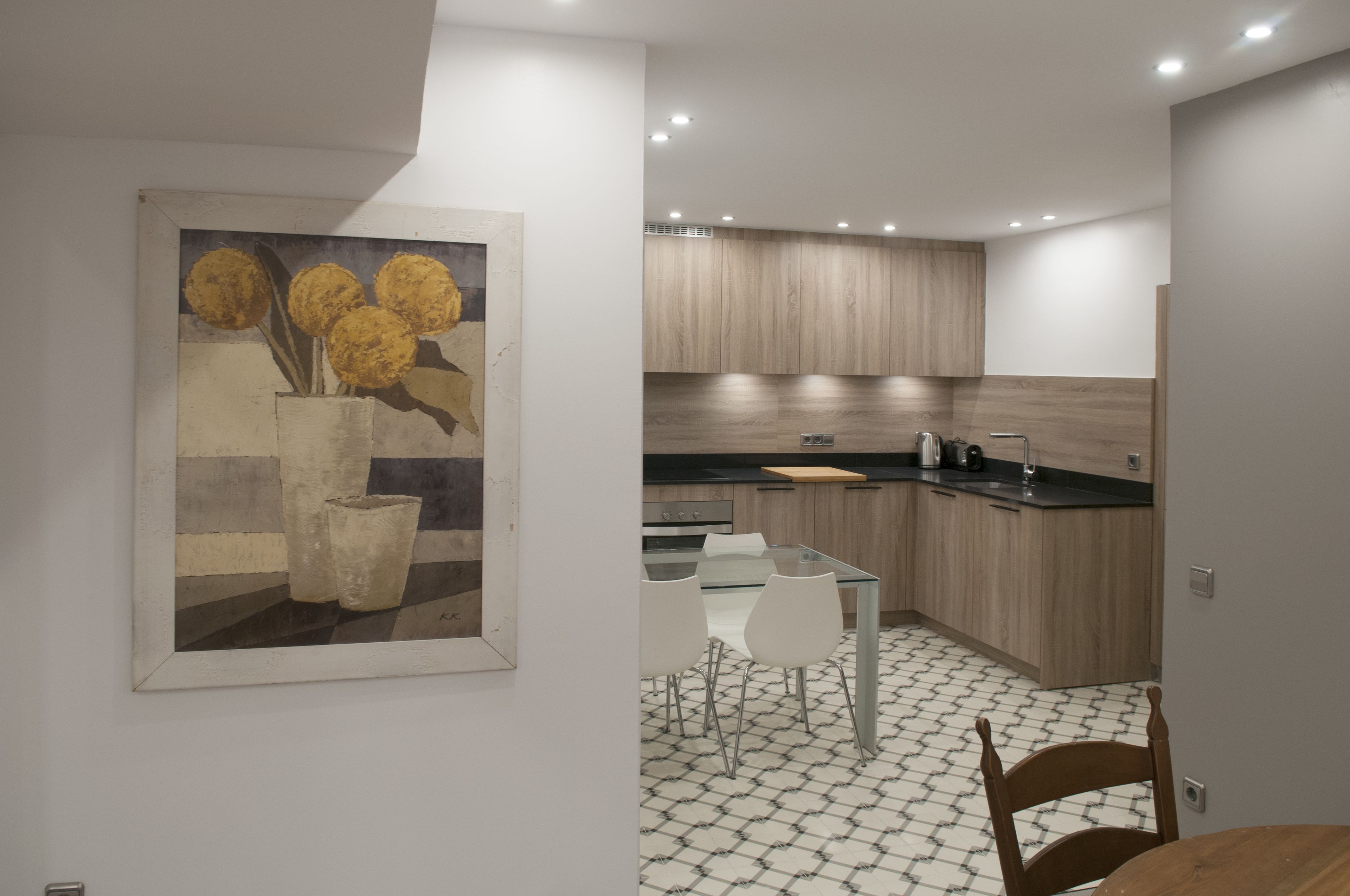A modern kitchen with wooden cabinets, a black countertop, and a tiled floor.