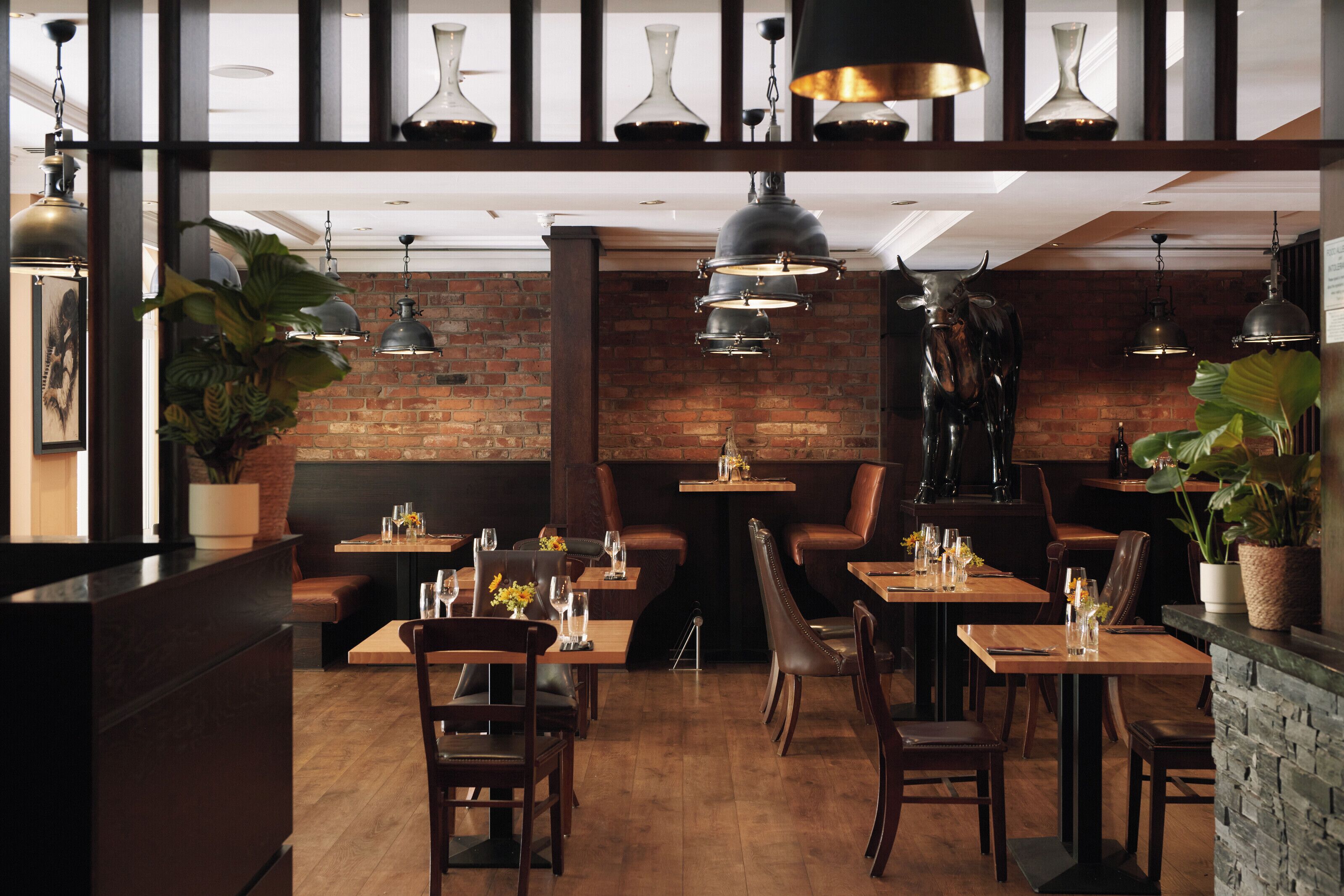 Un restaurant aux murs de briques, aux tables en bois et aux banquettes en cuir.
