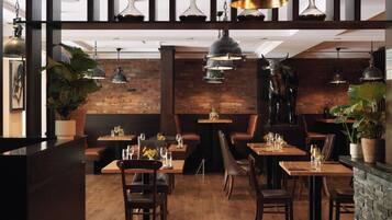 Un restaurant aux murs de briques, aux tables en bois et aux banquettes en cuir.