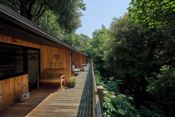 A wooden deck with outdoor seating, surrounded by dense greenery. - Fermain Valley Hotel (St. Peter Port)