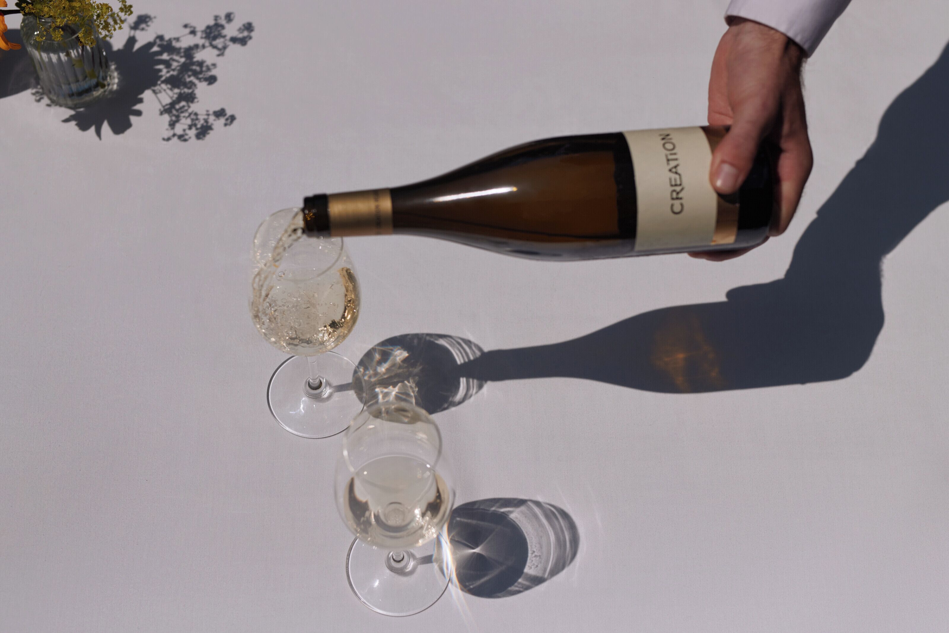 A hand pouring wine into a glass.