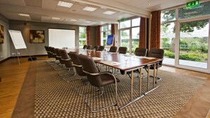 A conference room with a long table, chairs, a whiteboard, and large windows with curtains. - Fermain Valley Hotel (St. Peter Port)