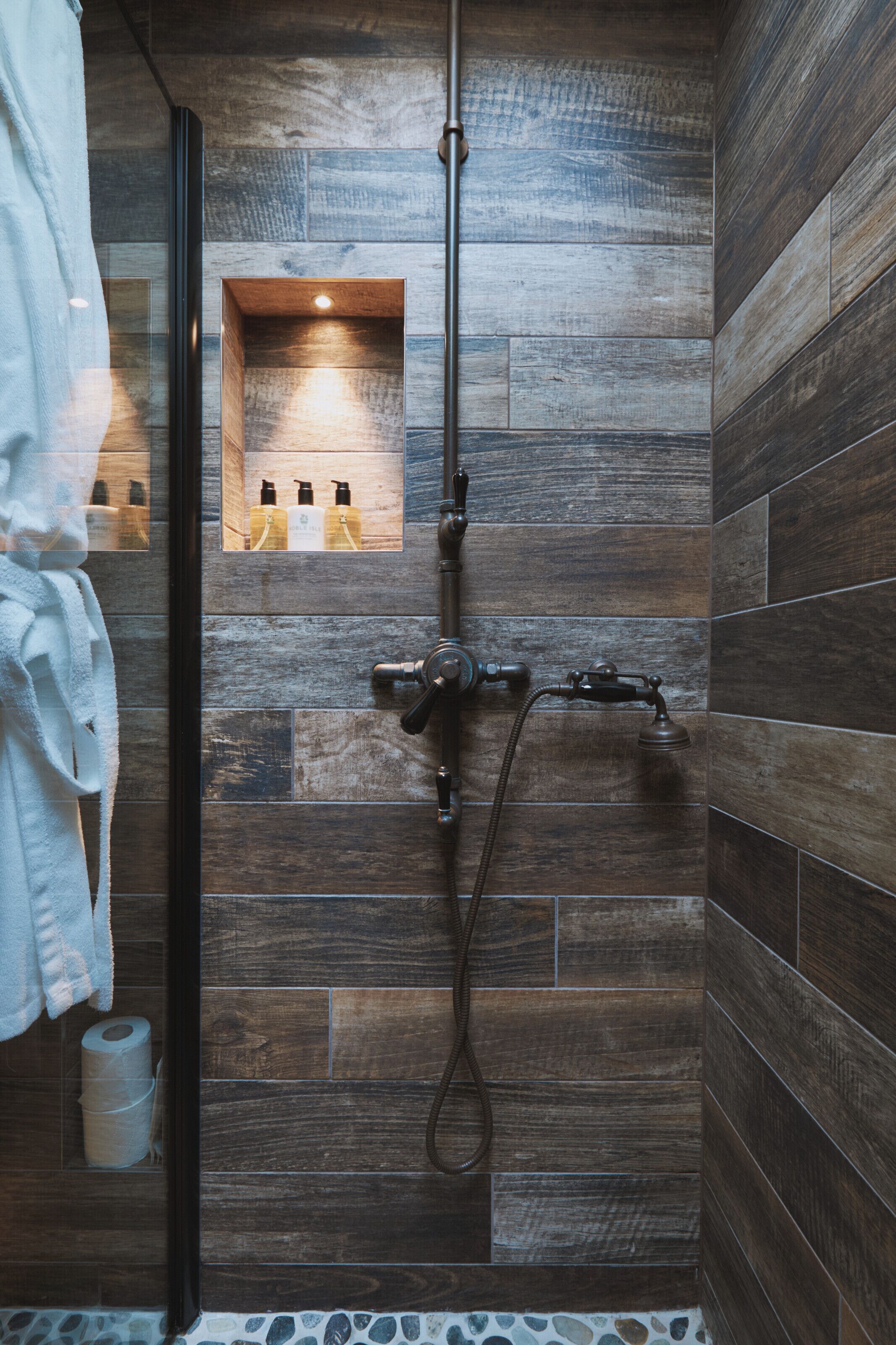 A bathroom with a shower, a towel rack, and a small shelf with toiletries.