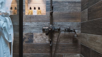 A bathroom with a shower, a towel rack, and a small shelf with toiletries.