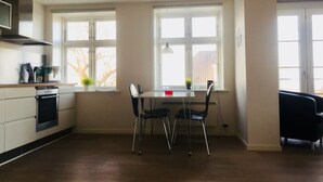 Cocina moderna con zona de comedor, ventanas amplias y una silla negra.