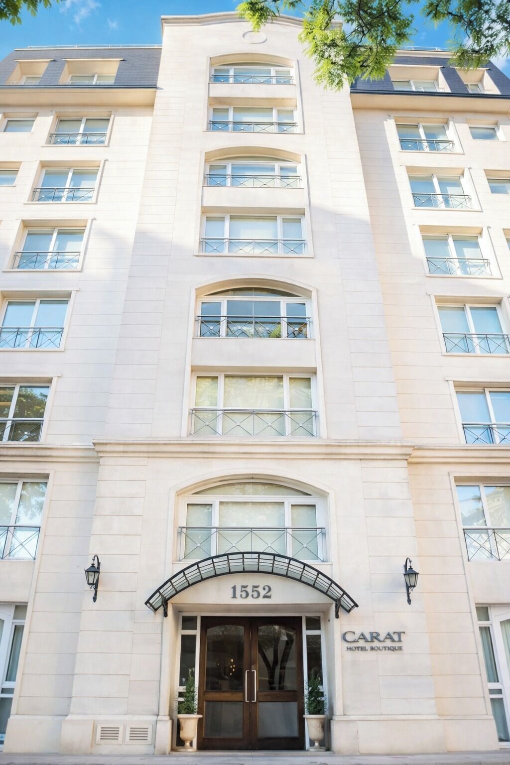 Entrada de un hotel con el número '1552' y el nombre 'CARAT HOTEL BOUTIQUE' sobre las puertas.