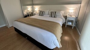 Una habitación de hotel moderna con una cama grande, mesitas de noche y un espejo.