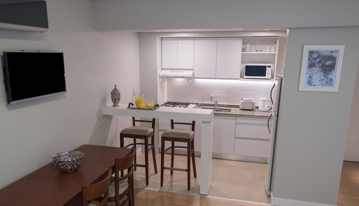 A compact kitchen with white cabinets, a microwave, and a small island with stools.