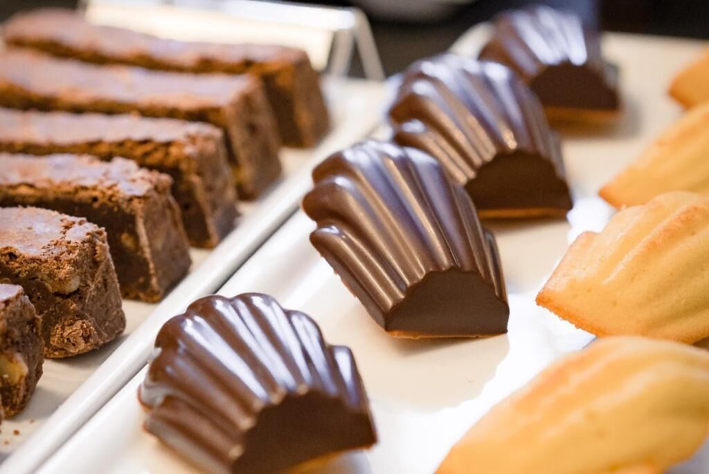 Una variedad de postres, entre ellos brownies y productos cubiertos de chocolate, dispuestos en una bandeja.