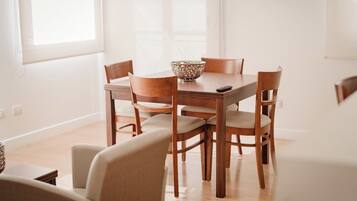 Uma área de refeições com mesa e cadeiras de madeira, uma tigela decorativa e um controle remoto sobre a mesa.