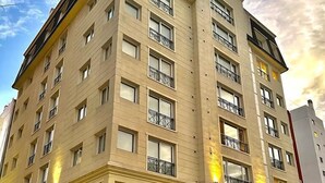 A multi-story hotel with balconies, outdoor seating, and a fountain. - Carat Apart Boutique (Rosario)