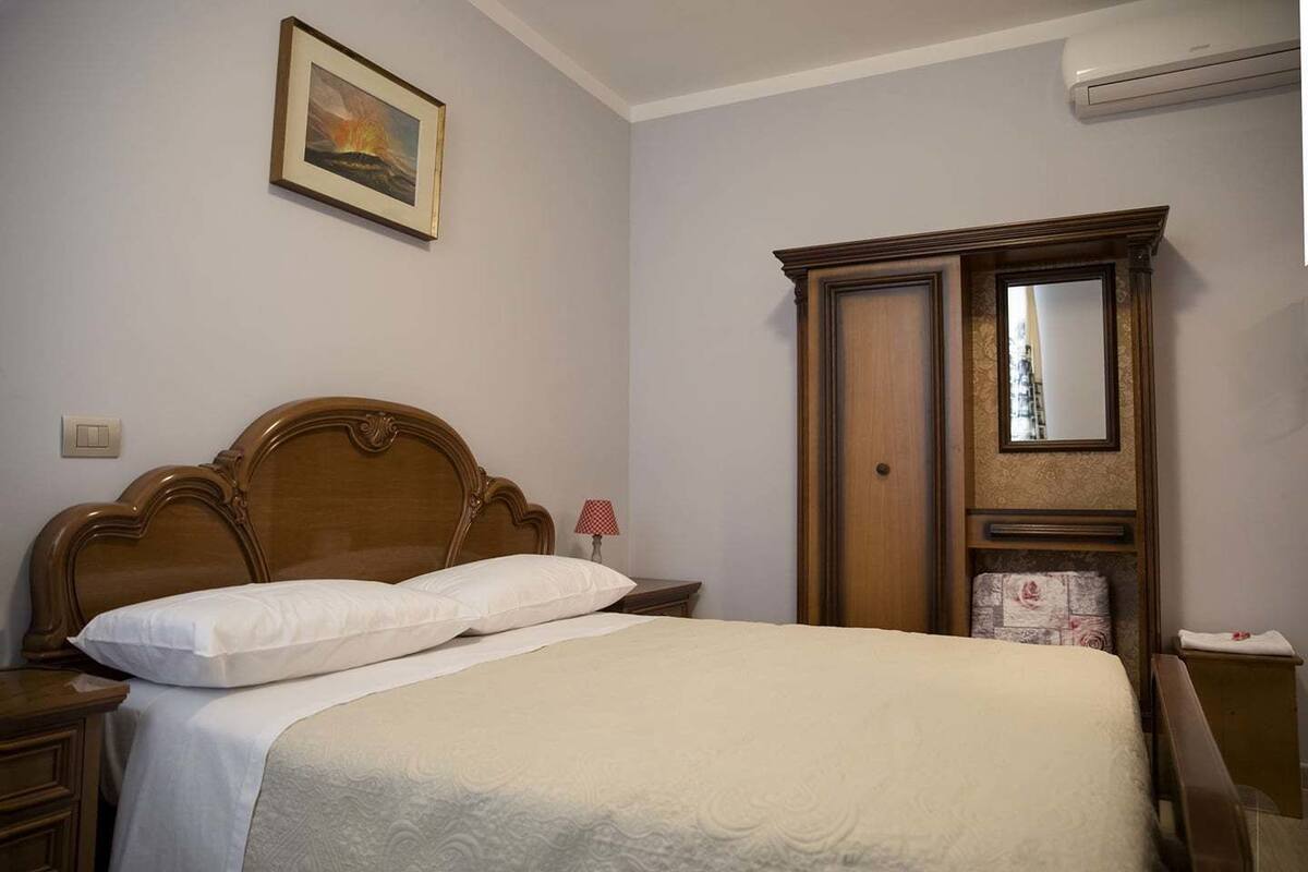 A neatly made bed with a wooden headboard, a bedside lamp, and a framed picture on the wall.