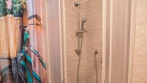 A shower with a glass door, a toilet, and a wall with a textured pattern. - Le Camere di Gio (Alba)