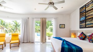 A hotel room with a bed, a ceiling fan, a large window with curtains, a balcony, and a view of palm trees. - Casa Susana by Playa Paradise (Playa del Carmen)