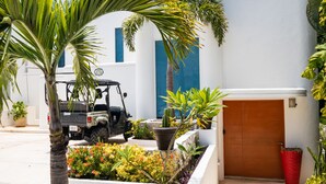 A modern building with a white facade and blue accents, a wooden door, and a parked vehicle. - Casa Susana by Playa Paradise (Playa del Carmen)