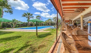 Zona de piscina con bar y asientos, rodeada de follaje y palmeras.