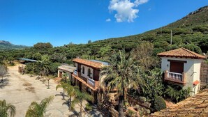 Un cadre rural caractérisé par une architecture traditionnelle, comprenant une maison avec un toit en tuiles et un petit bâtiment doté d’un balcon.