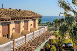A building with a tiled roof and balconies overlooking a coastal area. - Hotel Dulce Nombre (Tarifa)