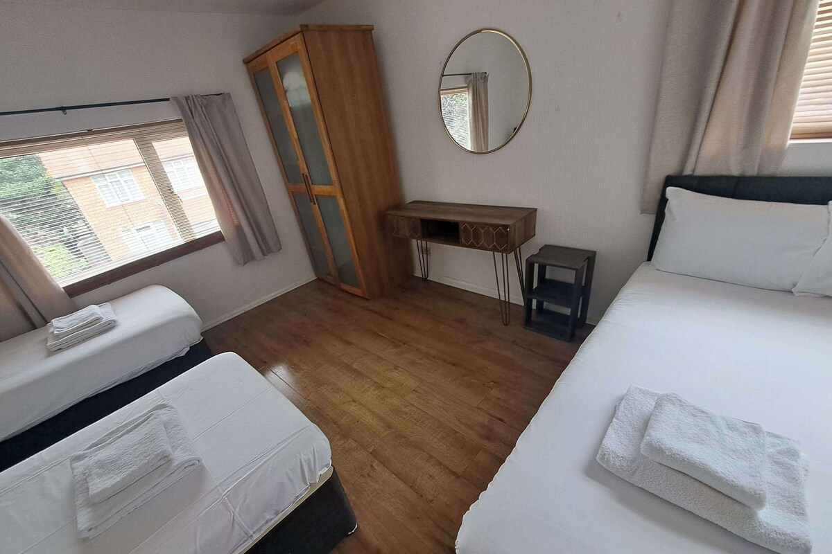Une chambre d’hôtel avec deux lits, un bureau, une armoire et une fenêtre avec des rideaux.