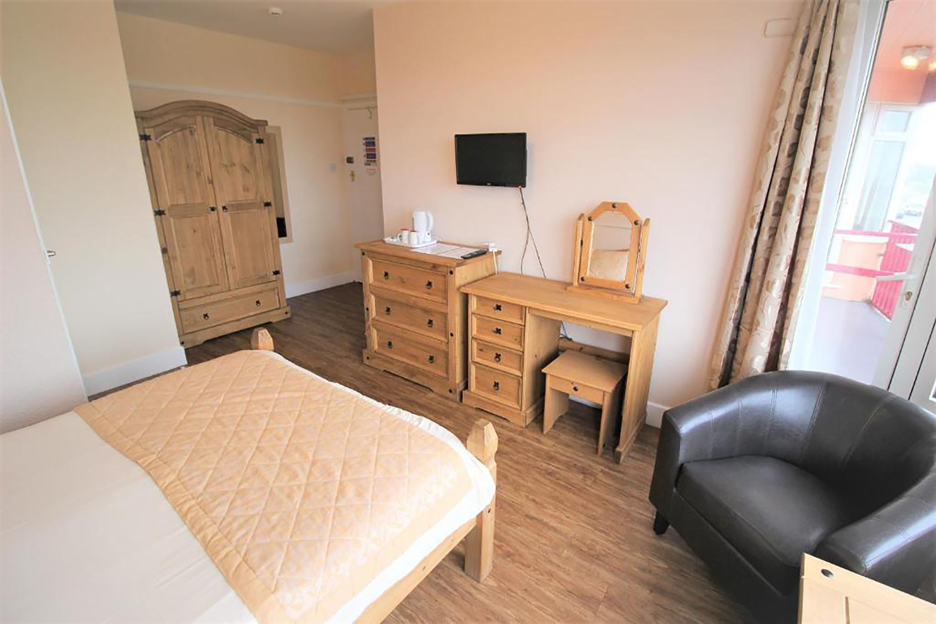 A bedroom with a bed, a desk, a chair, and a wardrobe.