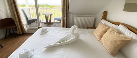A hotel room with a large bed, a view of the outdoors, a chair, and a table.