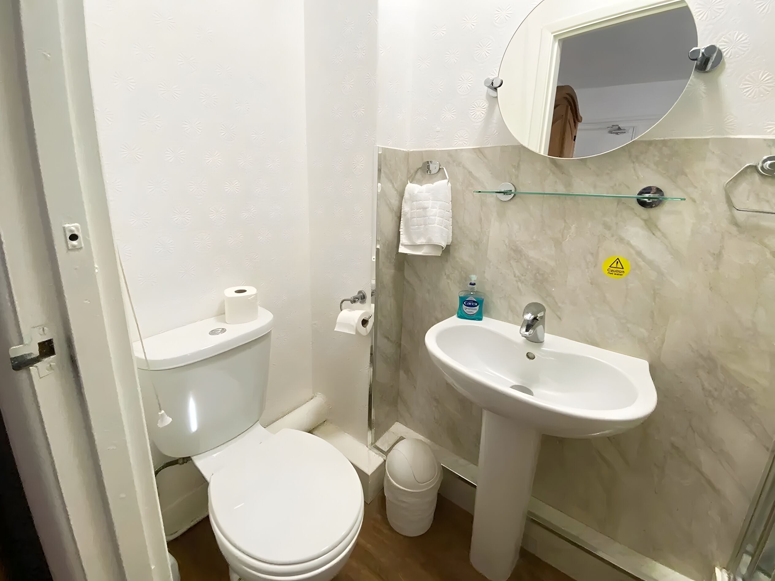A compact bathroom with a toilet, sink, and mirror.