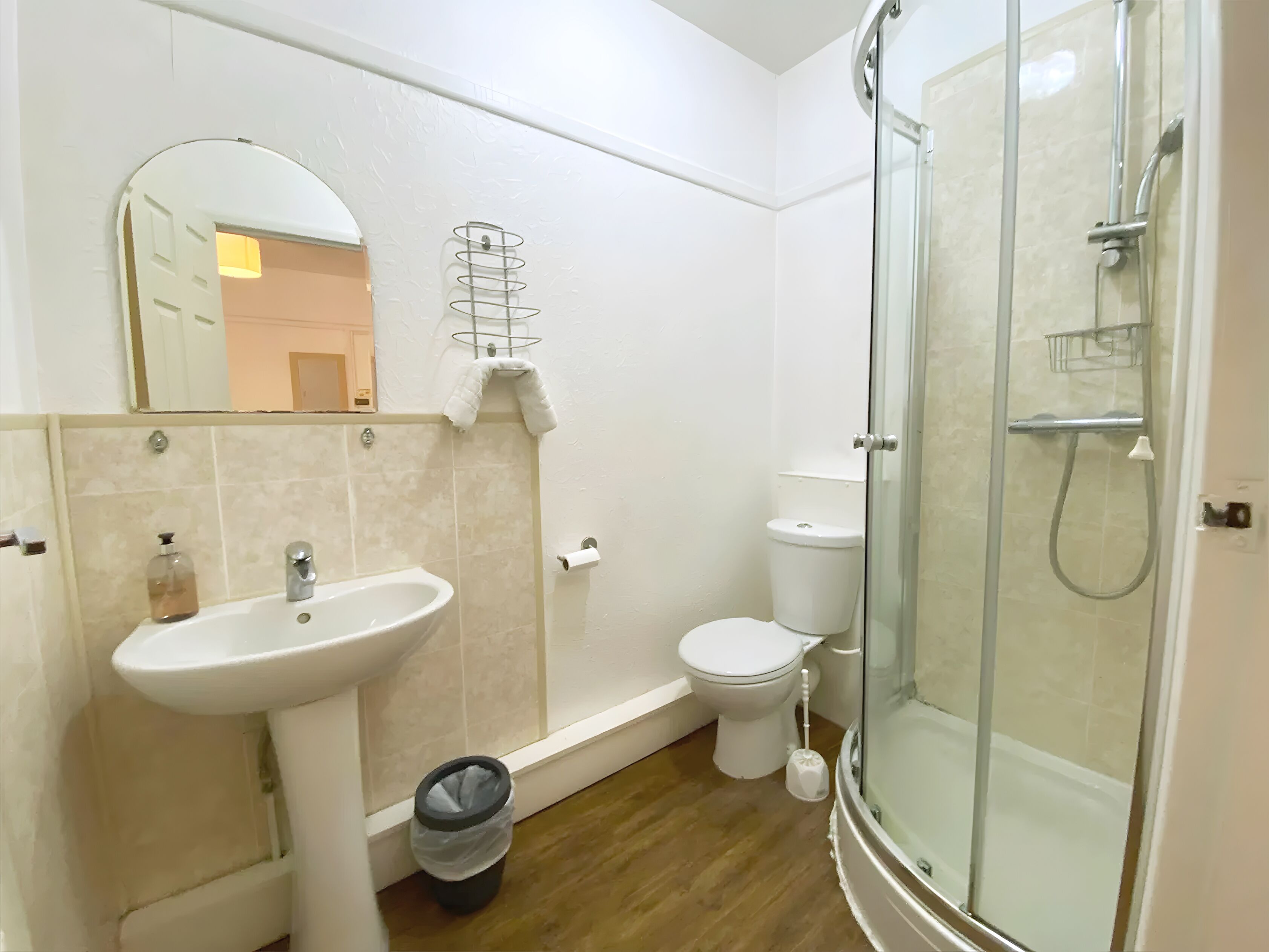 Un baño con lavamanos, inodoro y ducha con mampara de vidrio.
