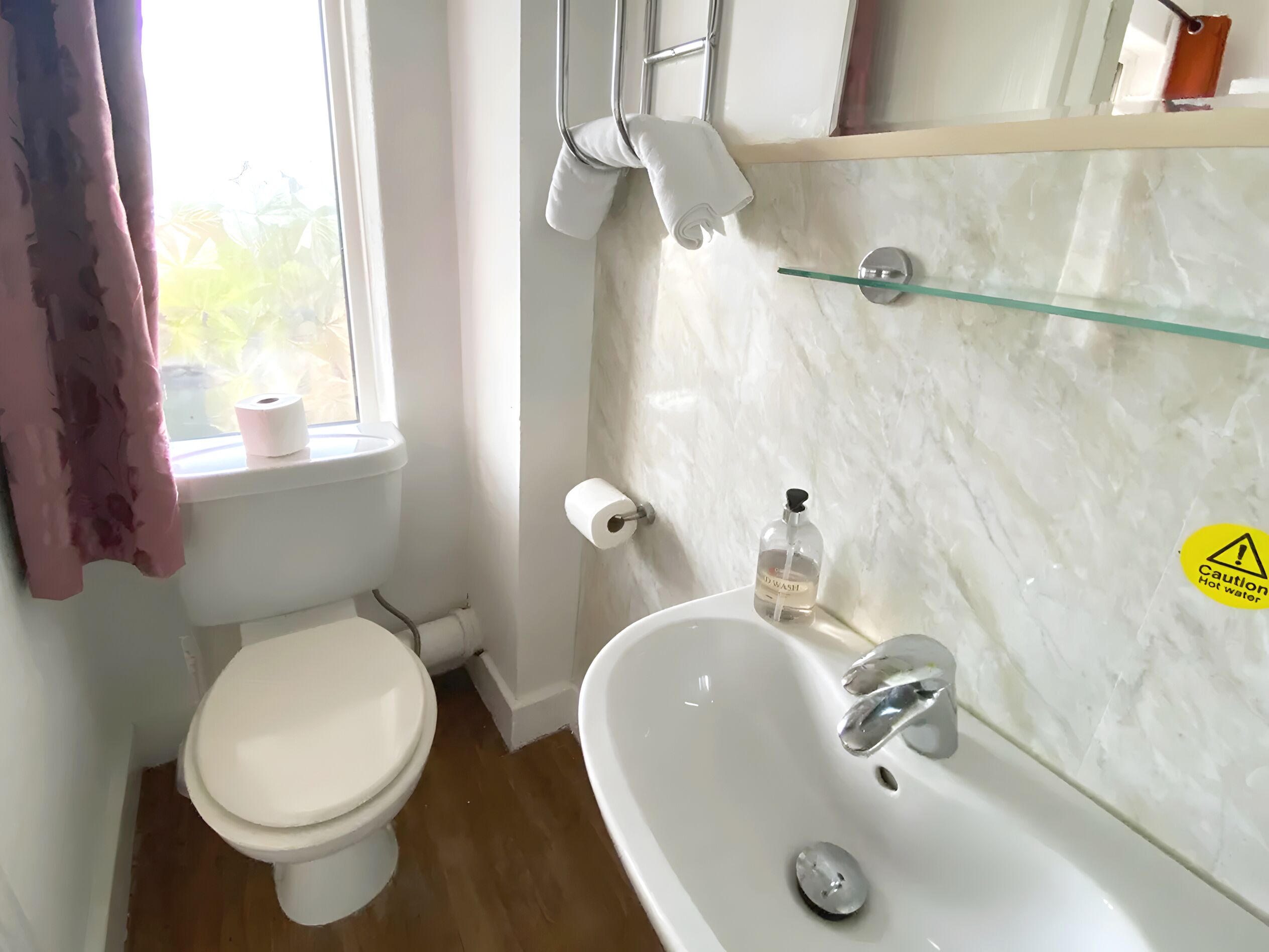 Un baño con inodoro, lavamanos y repisa de vidrio.