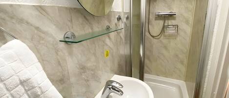 A bathroom with a white sink, a glass shower enclosure, and a mirror above the sink.