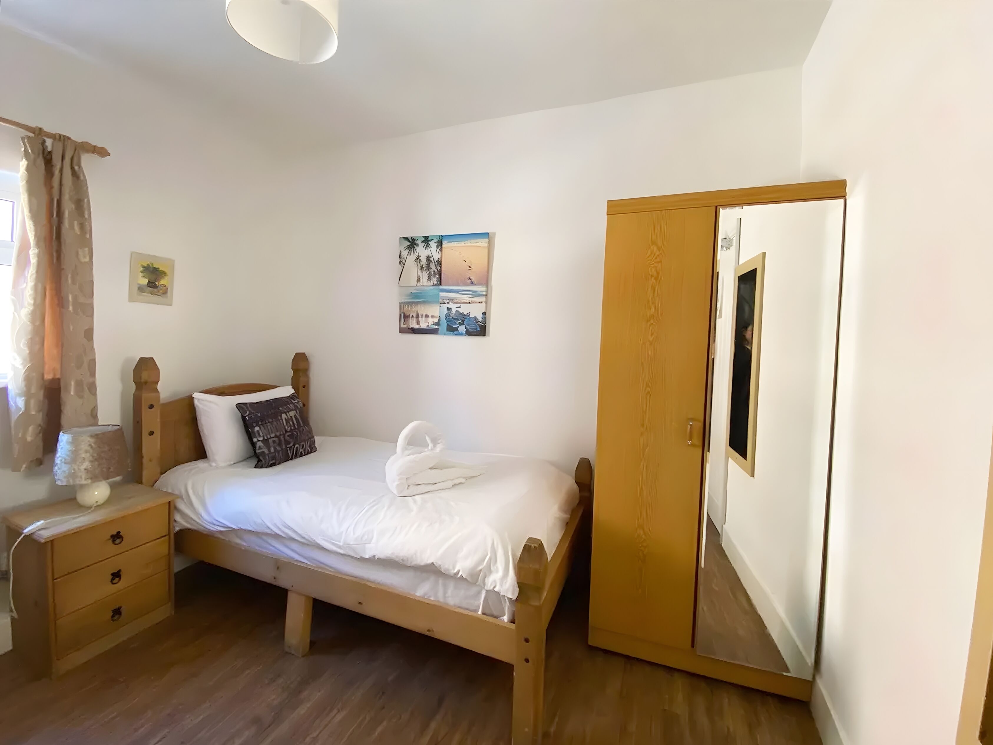 Une chambre à coucher avec un lit en bois, une table de chevet, une commode et un miroir.