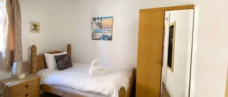 A bedroom with a wooden bed, a nightstand, a dresser, and a mirror.