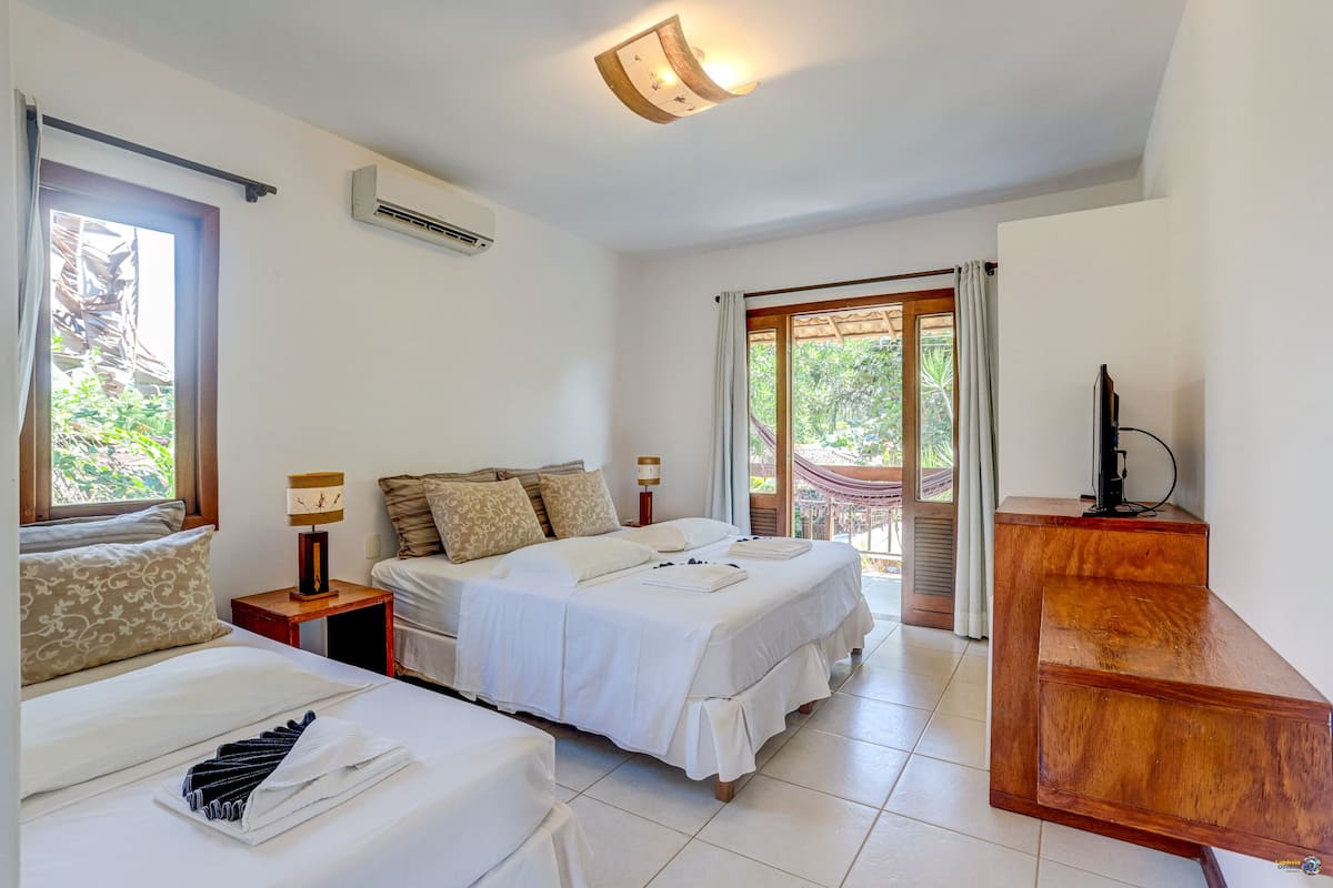 Quarto de hotel com cama, escrivaninha e televisão.