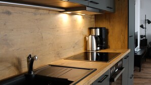 A modern kitchen with a wooden countertop, stainless steel appliances, and a built-in oven. - Haus Shiralee (Rostock)