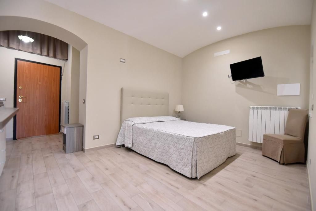Ein Schlafzimmer mit einem Bett, einem Sessel, einem an der Wand befestigten Fernseher und einer Heizung.
