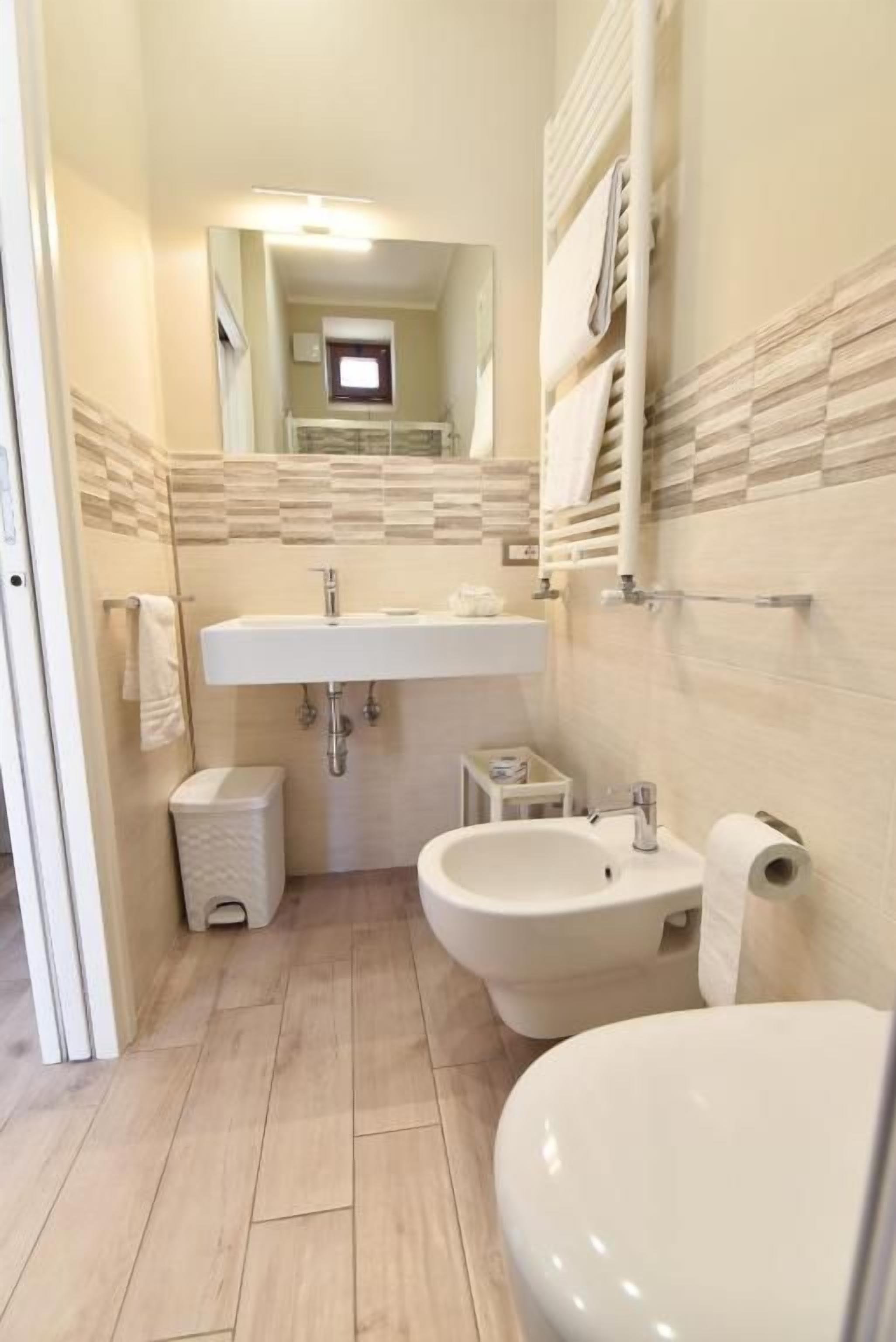 Une salle de bain équipée d’un lavabo, d’un bidet, de toilettes et d’un miroir.