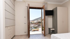 Une chambre d’hôtel avec un balcon, un lit, une télévision et une armoire.