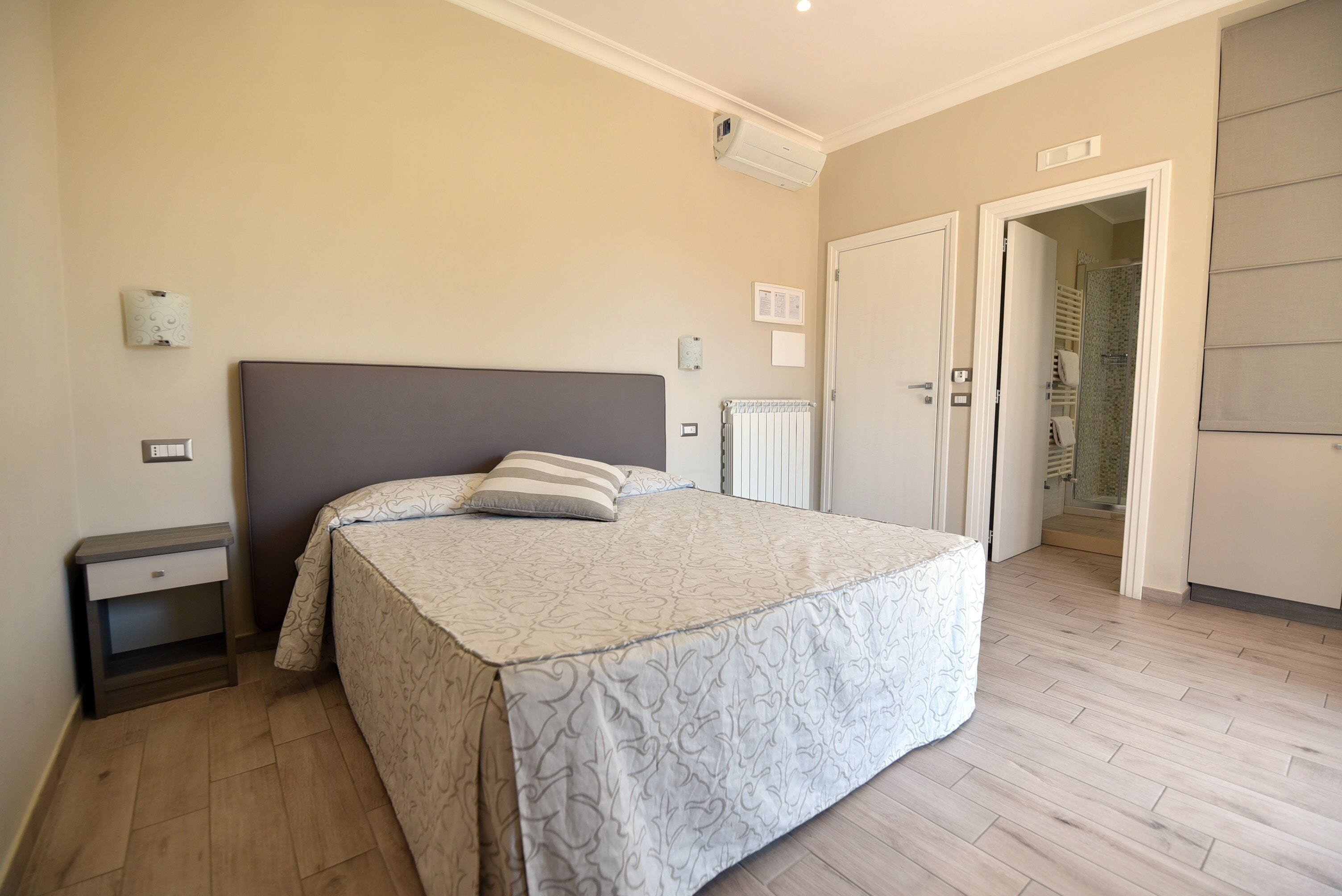 A bedroom with a bed, bedside table, and a radiator.