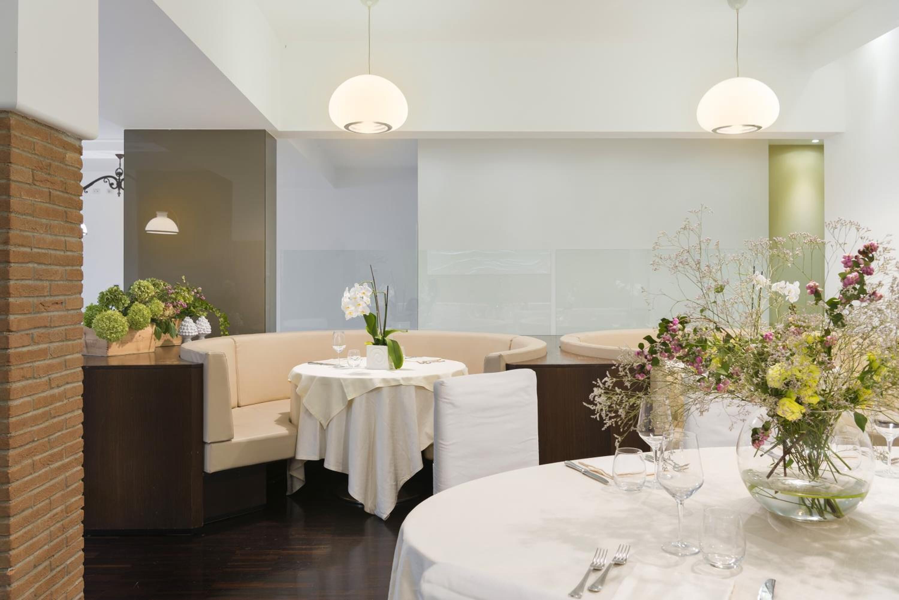 A restaurant with round tables, white tablecloths, and floral centerpieces.