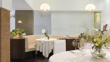 A restaurant with round tables, white tablecloths, and floral centerpieces.