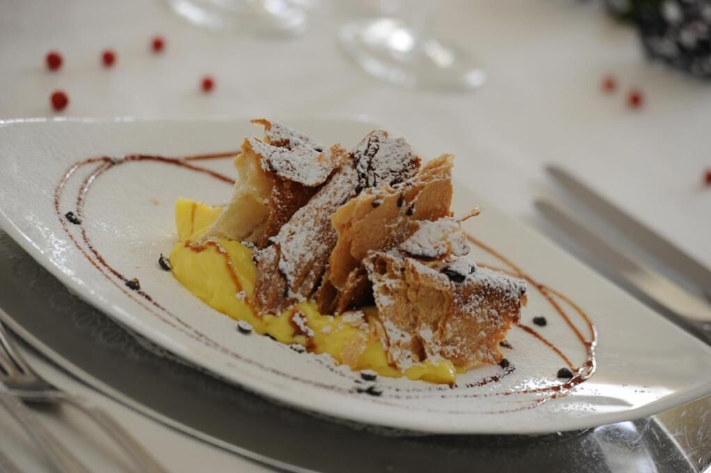 A dessert plate with a cake, fruit, and powdered sugar.